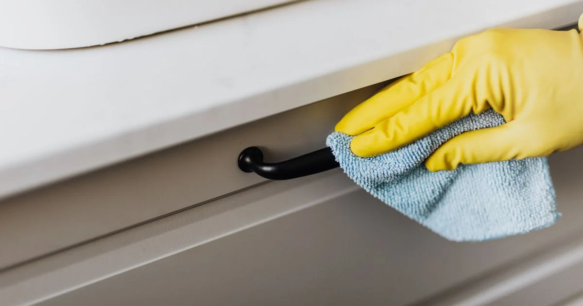 Cleaning cloth wiping cabinet handle with glove